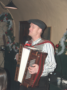 878157 Afbeelding van een accordeonist die optreedt tijdens het kerstdiner voor de medewerkers van het Volksbuurtmuseum ...